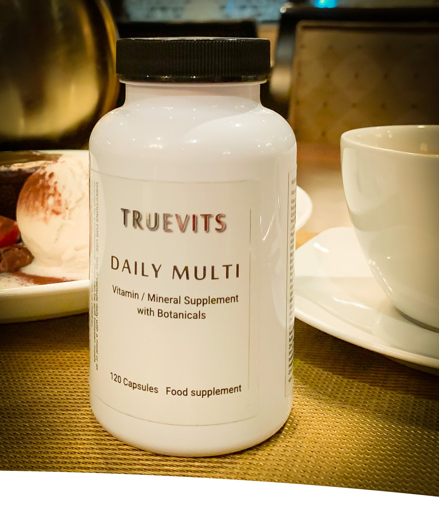 Daily-Multi-vitamin-mineral-supplement-on-dining-table-with-white-cup-of-coffee-on-sauser-and-ice-cream